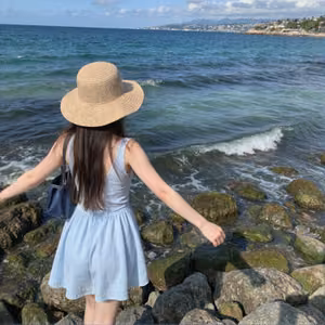 海边戴帽的少女背影